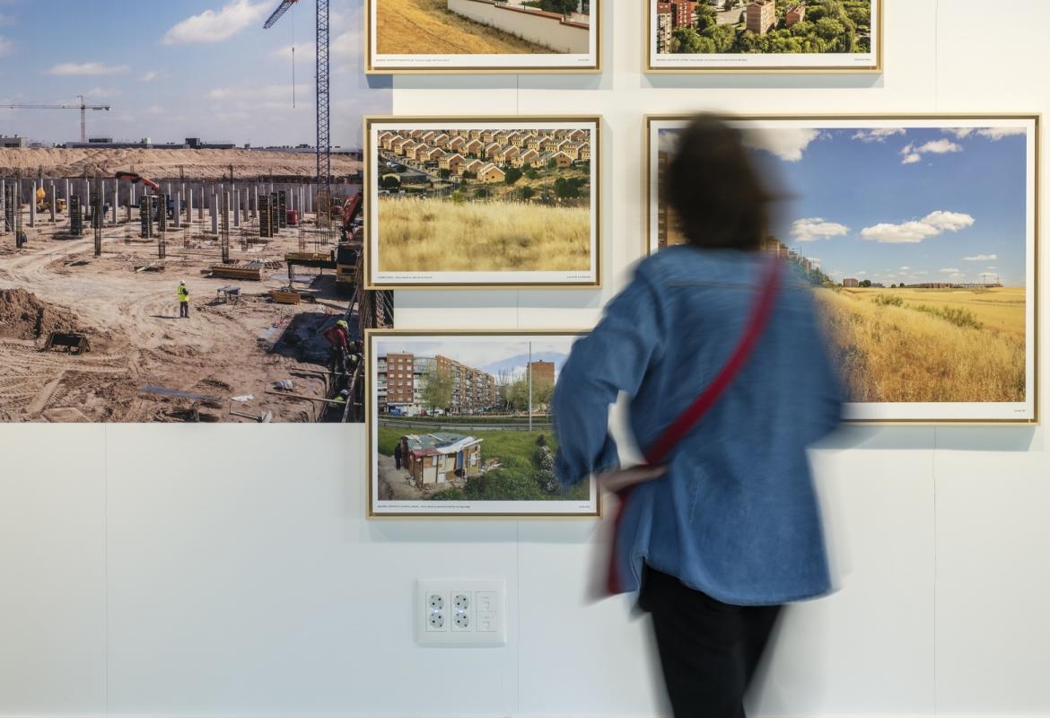 Una persona de espaldas observa algunas fotografías de la muestra Vistas Paisajes urbanos de la Comunidad de Madrid