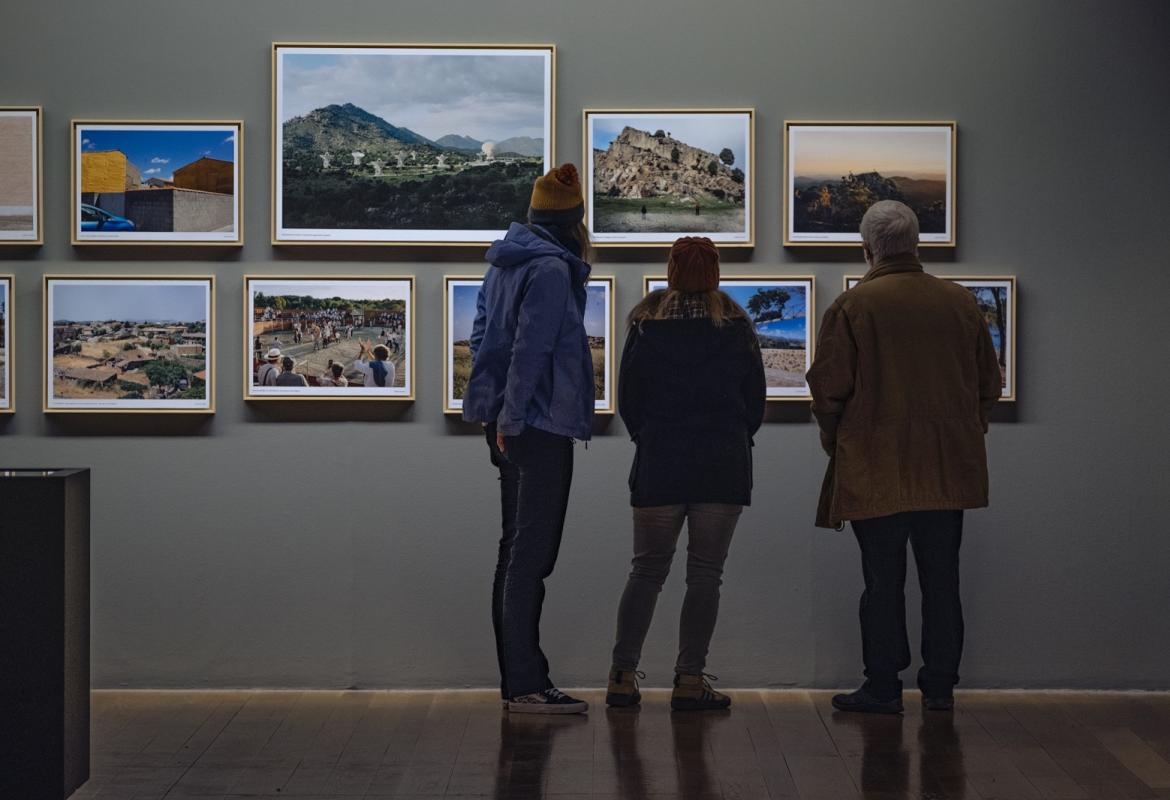Varios visitantes observan algunas de las fotografías de la muestra REGIÓN, Paisaje, fotografía y patrimonio