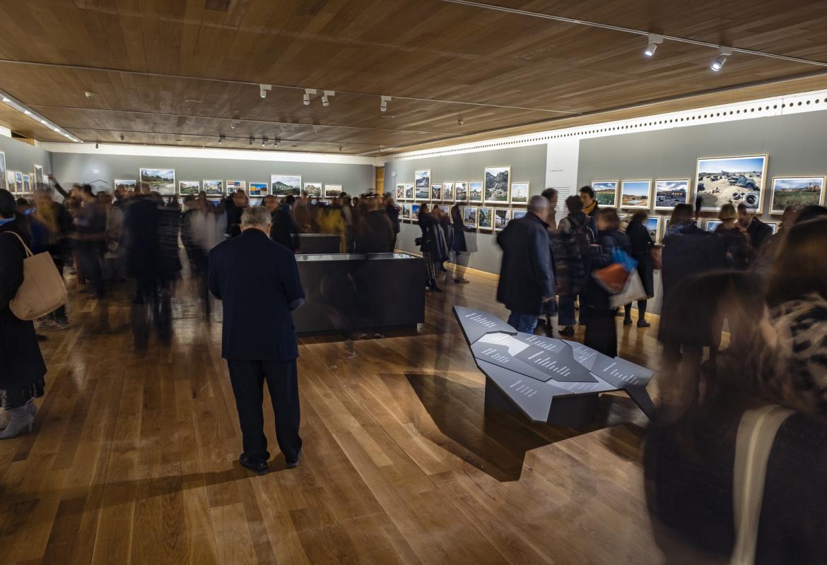 Panorámica de la sala de exposiciones con la muestra REGIÓN, Paisaje, fotografía y patrimonio, se aprecian sombras de visitantes