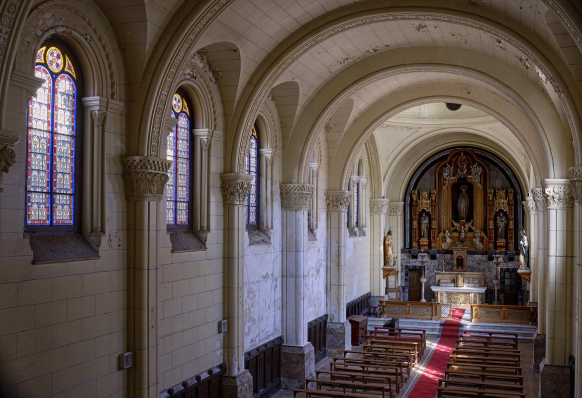 nave de iglesia con altar al fondo y ventanas acristaladas