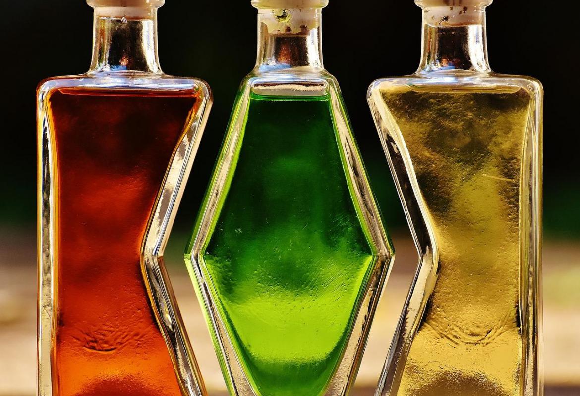 Tres botellas de cristal de distintas formas con líquidos de colores en su interior