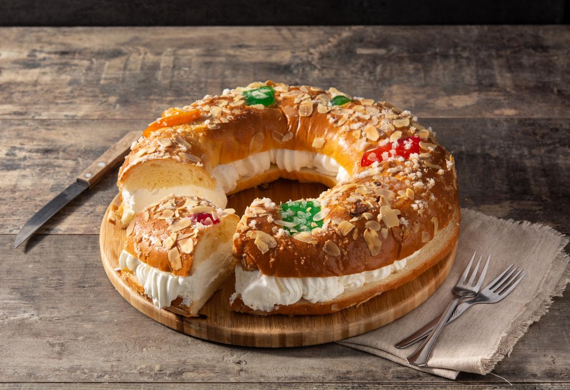 Roscón relleno con nata y un trozo cortado, sobre una mesa de madera