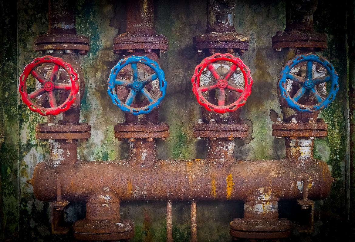 Grandes tuberías oxidadas por fuera con cuatro grandes llaves de color rojo y azul