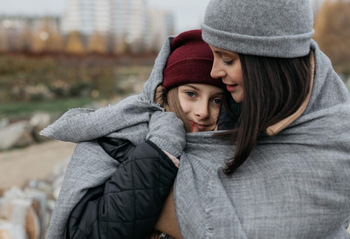 Dos chicas abrazadas y con varias capas de ropa en invierno