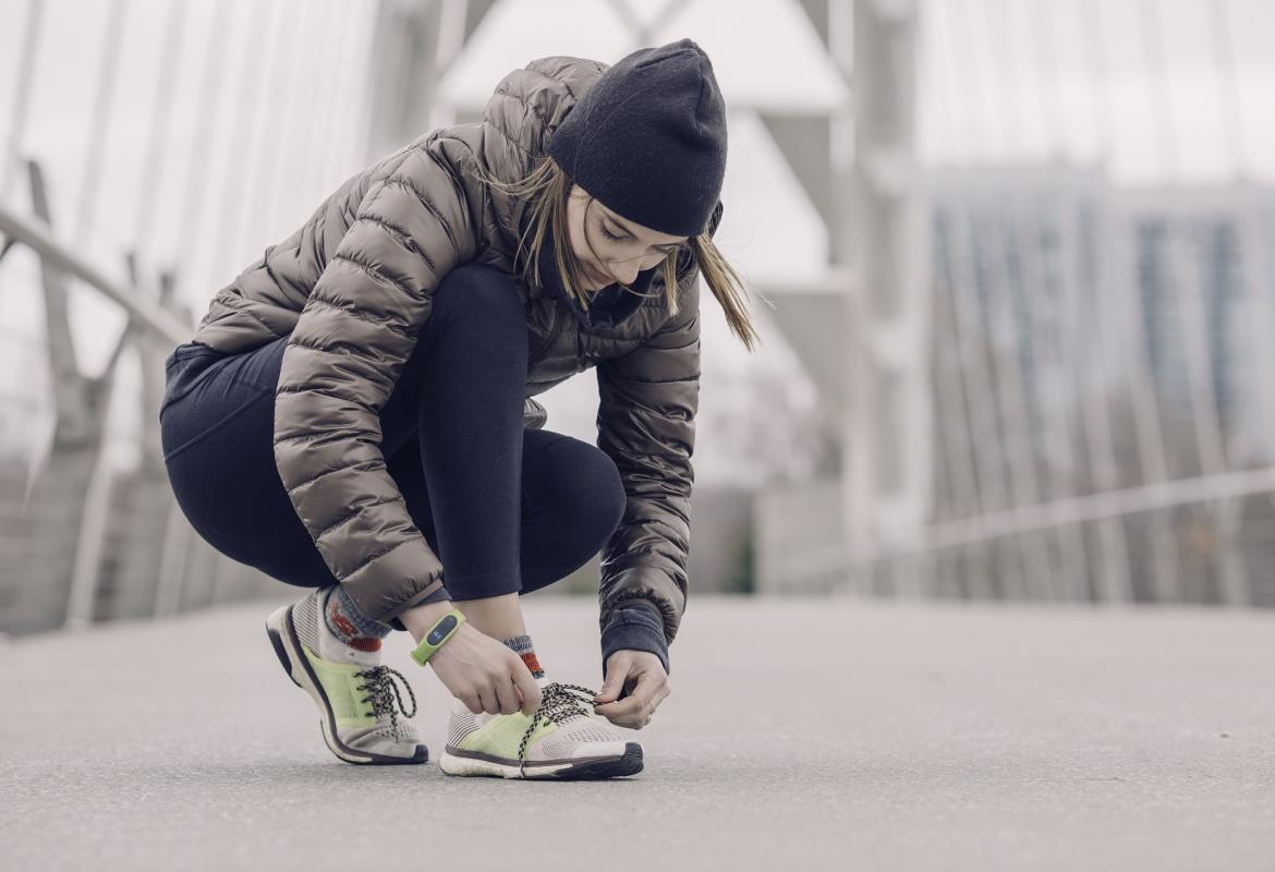 Chica agachada abrochándose la zapatilla de deporte