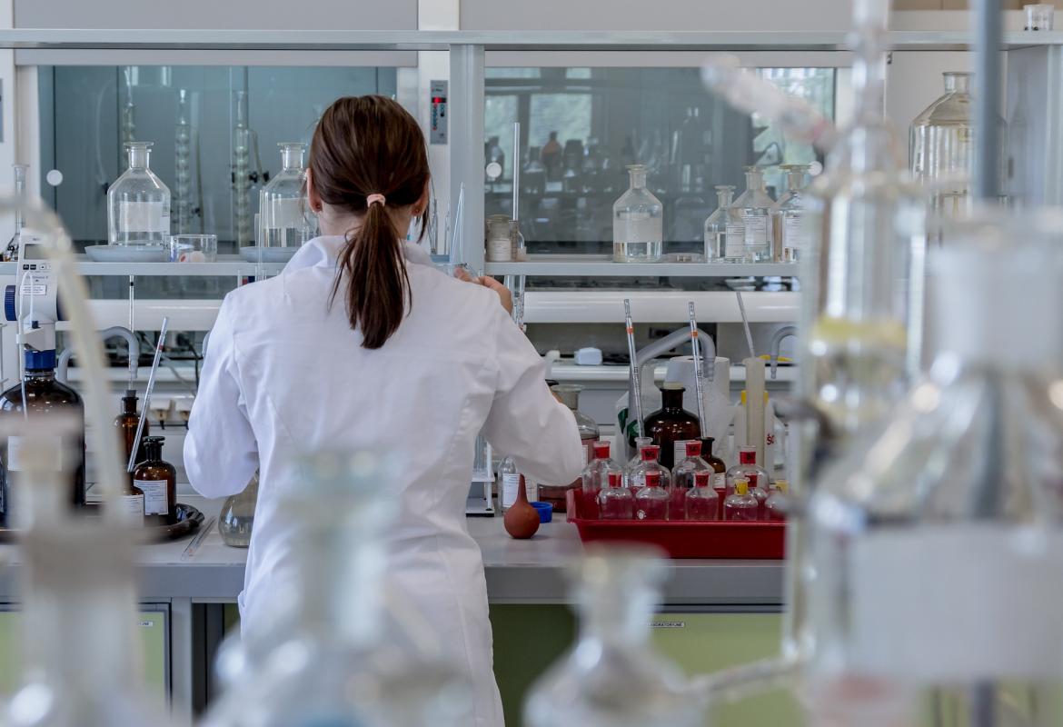 Mujer técnico de laboratorio con bata blanca de espaldas trabajando