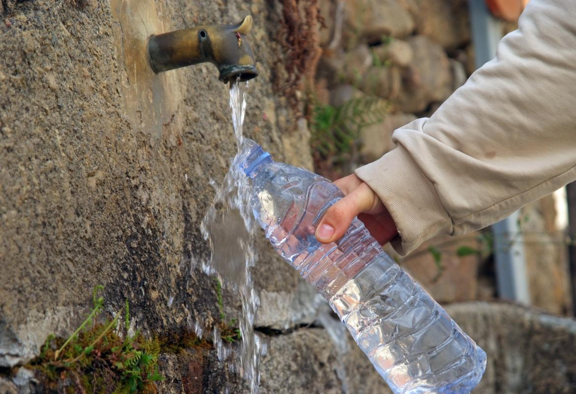 Persona rellenando una botella en una fuente