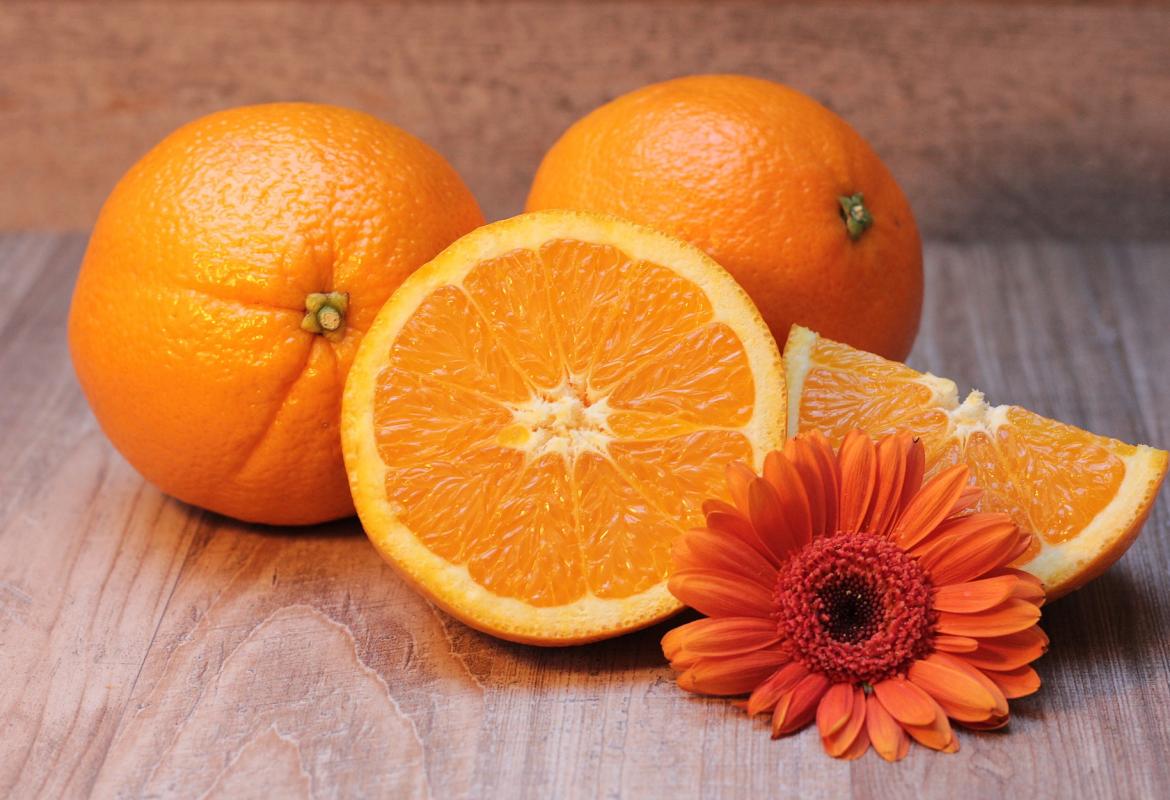 Naranjas enteras y troceadas y una flor