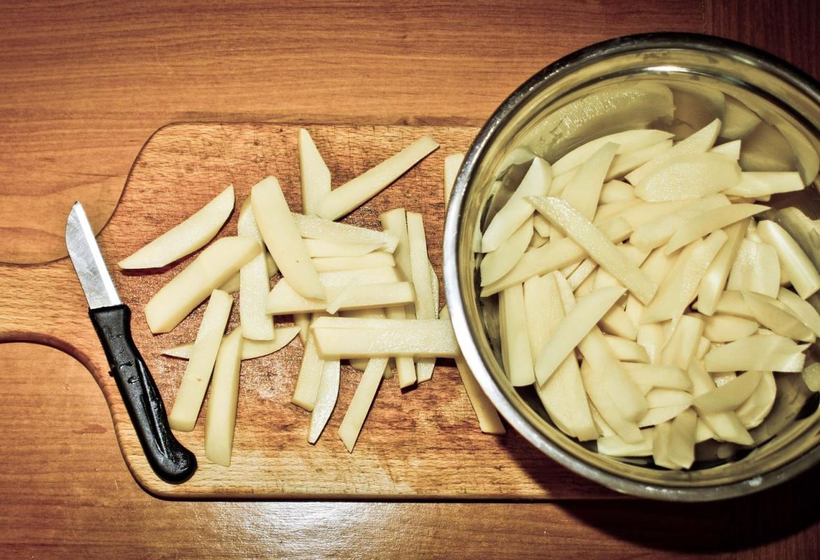 Patatas cortadas con pelador sobre una tabla de cortar