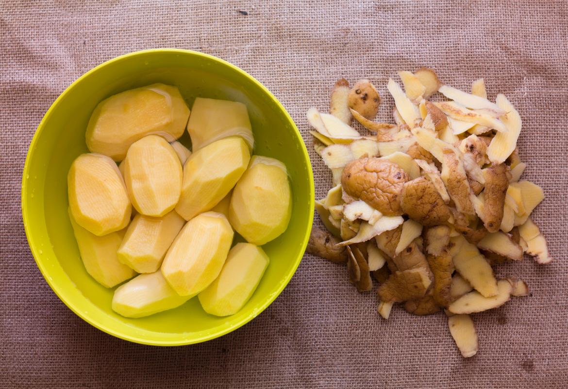 Cuenco con patatas enteras peladas, y piel separada del cuenco