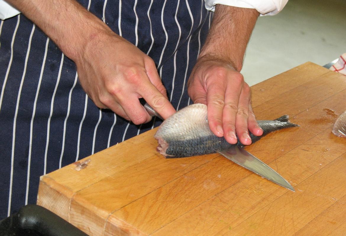 Manos cortando un trozo de pescado