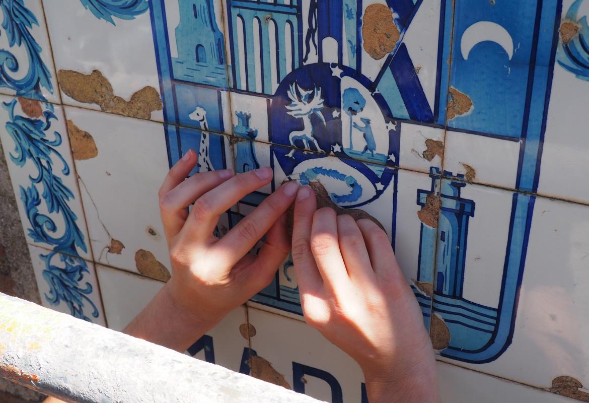 manos interviniendo sobre un escudo de azulejos en mal estado de conservación