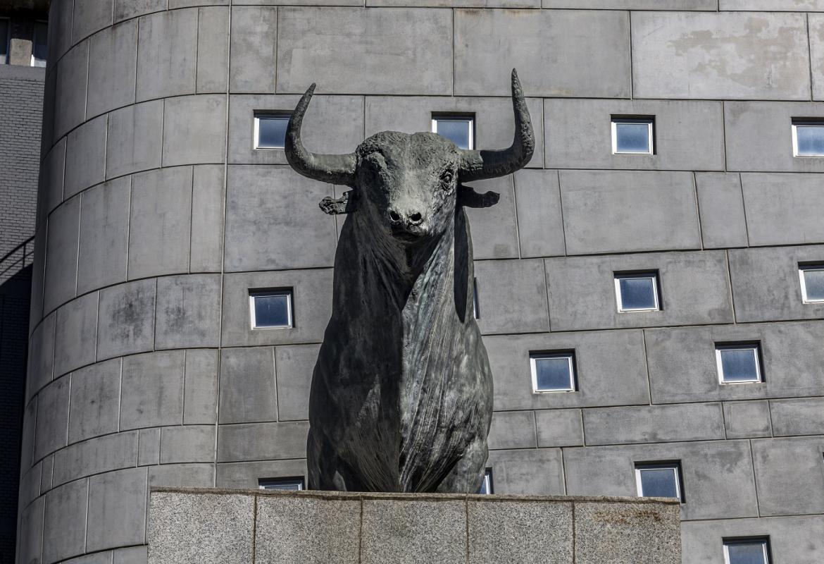 escultura de un toro frente a un edificio gris con ventanales