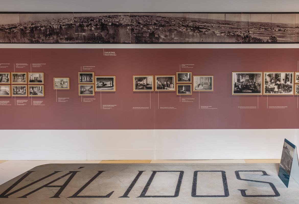 detalle placa de edificio en primer plano y fotografías sobre pared en una sala de exposiciones