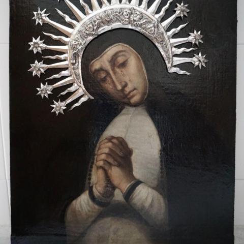 imagen de una pintura representando a la virgen en posición de oración llorando y vistiendo corona de plata