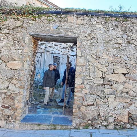 Estado inicial. Puerta – reja en el muro del patio norte. Elementos espurios y degradación constructiva imagen de dos hombres atravesando la puerta de una fachada de piedra