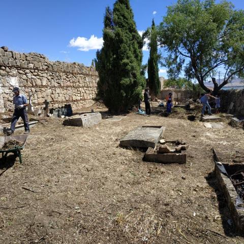 Imagen de recinto amurallado con árboles y restos de tumbas durante su intervención arqueológica