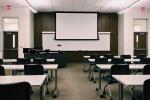 aula de formación con mesas, sillas y pizarra blanca al fondo